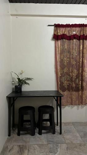 een zwarte tafel met twee krukken en een gordijn bij Huddle Pad in Baguio
