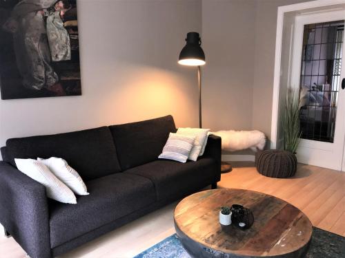 sala de estar con sofá negro y mesa de madera en Gezellige benedenwoning Singel en Dordrecht