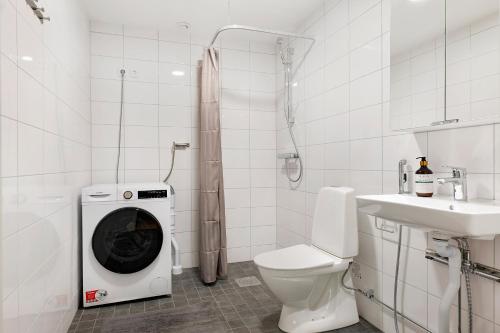 a white bathroom with a washing machine in a toilet at Guestly Homes - 1BR Corporate Comfort in Boden