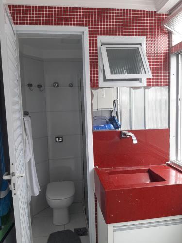 a bathroom with a red sink and a toilet at Apto Guaruja Astúrias in Guarujá