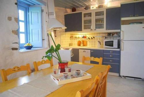 a kitchen with a wooden table and a white refrigerator at Paros Traditional Nest Cozy Paroikia Delight in Parikia