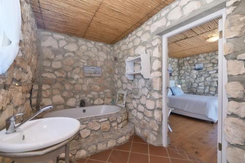 uma casa de banho em pedra com um lavatório e uma banheira em Seahaven em Arniston