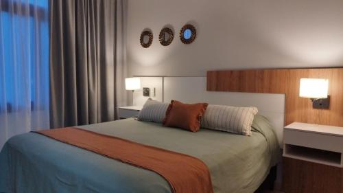 a bedroom with a bed with two lights on the wall at Lake 360 Apart Villa Carlos Paz in La Cuesta