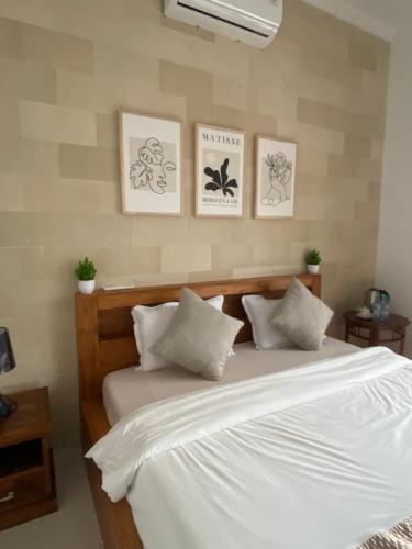 1 dormitorio con 1 cama blanca y 4 cuadros en la pared en Batur Exotic Villa, en Kubupenlokan