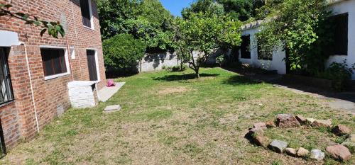 un patio vacío junto a un edificio de ladrillo con un árbol en El buen verano, en Ciudad de la Costa