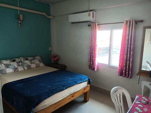 um quarto com uma cama com um edredão azul e uma janela em หอพักบ้านชูใจ em Phitsanulok