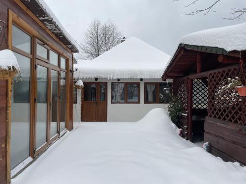 a house covered in snow next to a building at Casa Ceteras in Cavnic