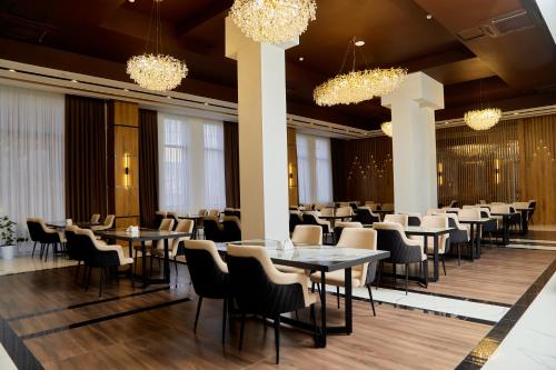 une salle à manger avec des tables, des chaises et des lustres dans l'établissement Grand Plaza Hotel Samarkand, à Samarcande