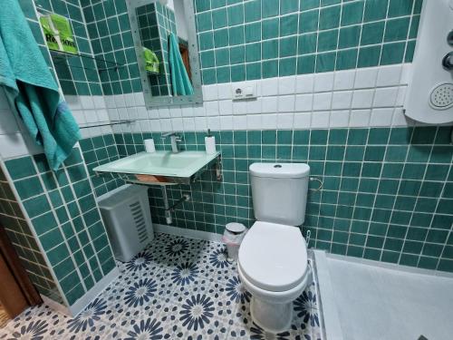 a green tiled bathroom with a toilet and a sink at Ganado26 in Sanlúcar de Barrameda