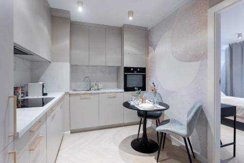 uma cozinha com armários brancos e uma pequena mesa em Grzybowska Rooms by Sofija em Varsóvia