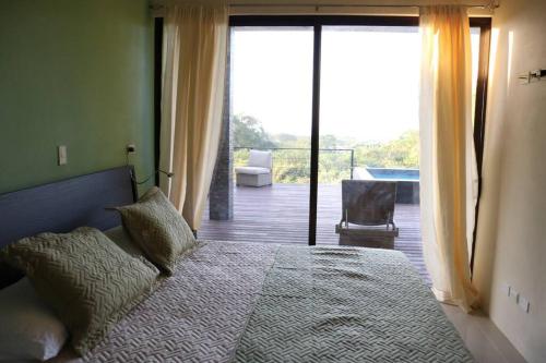 Schlafzimmer mit einem Bett und Blick auf einen Balkon in der Unterkunft Casa Mon Coeur-Playa Del Coco Ocean View in Coco