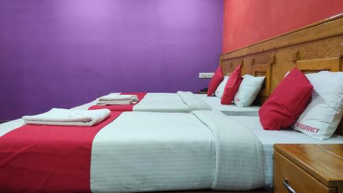 two beds with red and white pillows in a room at SM Residency in Coimbatore