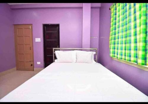 1 dormitorio con paredes moradas y 1 cama con sábanas blancas en Barsha guest house en Bolpur