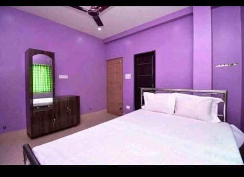 Dormitorio púrpura con cama y espejo en Barsha guest house en Bolpur