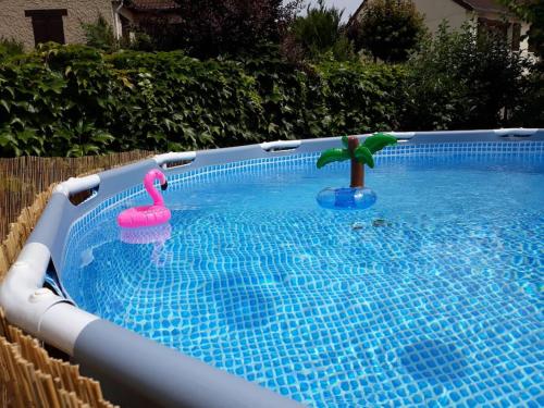 a swimming pool with two toy flamingos and a palm tree at Charmante maison, 40mn de Paris in Triel-sur-Seine
