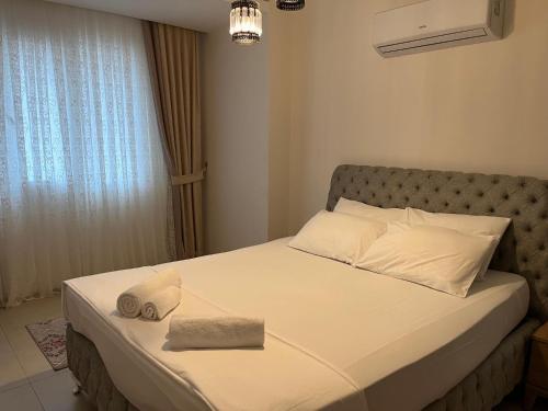 1 dormitorio con 1 cama con sábanas blancas y ventana en Residence 5 min to Naula Ancient City and Beach, en Mahmutlar