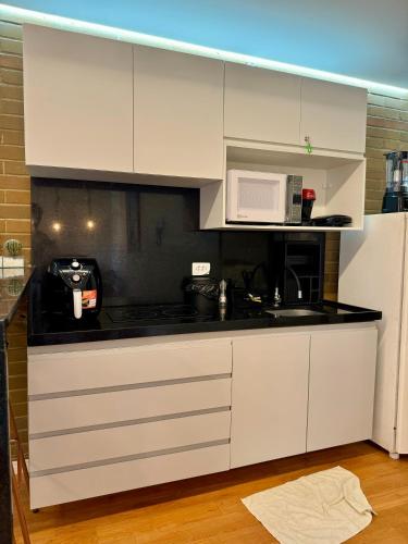 a kitchen with white cabinets and a microwave at EcoFlat Moderno e Aconchegante in Bonito