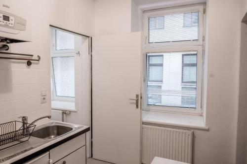 eine weiße Küche mit einem Waschbecken und einem Fenster in der Unterkunft Quiet Apartment - Vienna in Wien