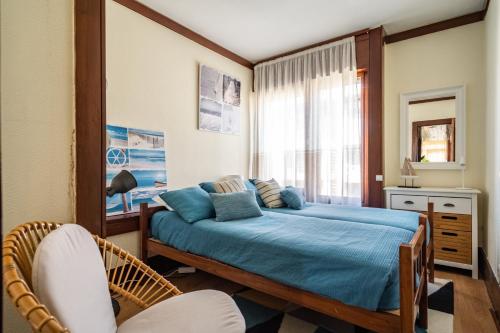 - une chambre avec un lit doté de draps bleus et une fenêtre dans l'établissement Akisol Troia Retreat, à Tróia