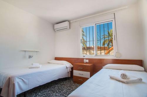 two beds in a room with a window at Villa Corina - Plusholidays in Ifach