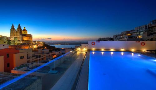 a pool on the roof of a building at night at Pergola Hotel & Spa in Mellieħa