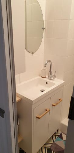 a white bathroom with a sink and a mirror at Maison de ville Angoulêmoise in Angoulême