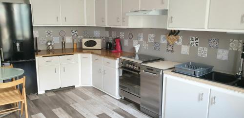 une cuisine avec des armoires blanches et des appareils en acier inoxydable dans l'établissement Maison de ville Angoulêmoise, à Angoulême