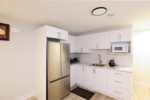 uma cozinha com armários brancos e um frigorífico de aço inoxidável em Luxury Vacation Space em Moncton