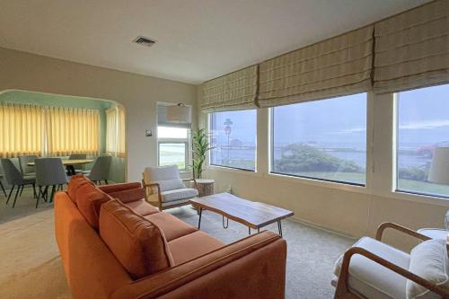 a living room with couches and a table and windows at Pacific Princess in Crescent City