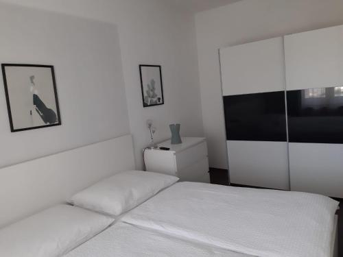 a white bedroom with a bed and a tv at Ferienwohnung Leithaberg in Eisenstadt