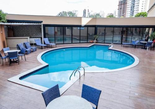 a large swimming pool with chairs and a table at Hotel Inter Cuiaba in Cuiabá