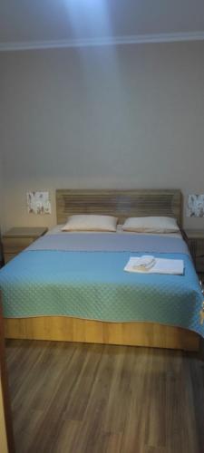 een slaapkamer met een bed met blauwe lakens en een houten vloer bij Guga gold in Tbilisi City