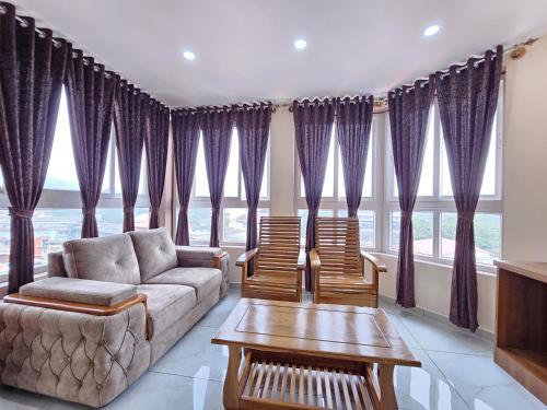 a living room with purple curtains and a couch and chairs at Navarathna Comforts in Madikeri
