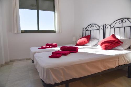 twee bedden in een kamer met rode kussens erop bij Ático en Mar de Nerja in Nerja