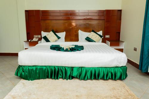 a bedroom with a large white bed with a green skirt at Kerama Silent Lodge in Arusha