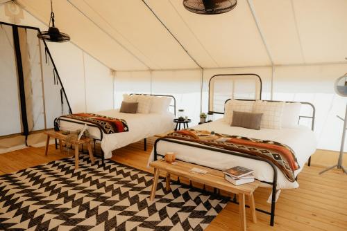 a room with two beds and a table and a rug at Glamping Tents 2 Queens at Lake Guntersville State Park in Guntersville