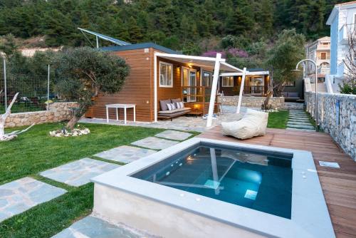 un patio trasero con piscina y una casa en Junam Private Beachfront Cabins en Ayios Nikitas