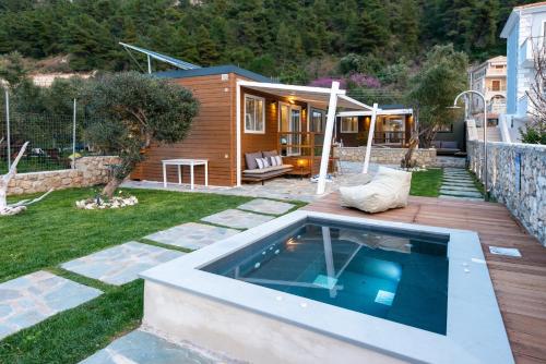 un patio trasero con piscina y una casa en Junam Private Beachfront Cabins, en Agios Nikitas