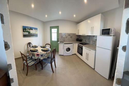 a kitchen with a table and chairs and a white refrigerator at Casa Porta Velha 2 Bed in Tavira