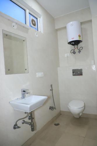 a bathroom with a sink and a toilet and a mirror at Hotel Moon Residency Near Yashobhoomi Convention Centre in New Delhi