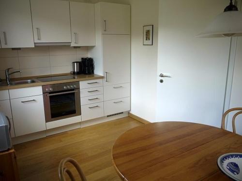 a kitchen with white cabinets and a wooden table at Ferienwohnung Axeli Knapp in Schleswig