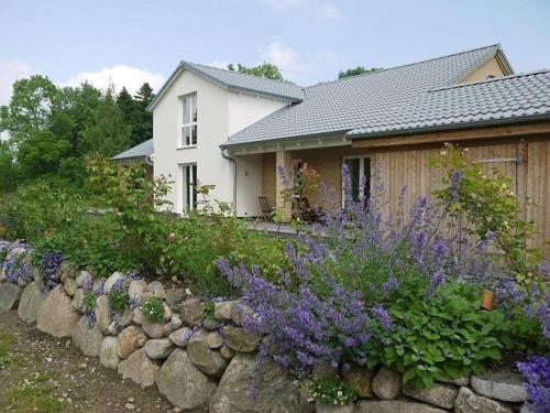 a house with a stone retaining wall and purple flowers at Ferienwohnung Axeli Knapp in Schleswig