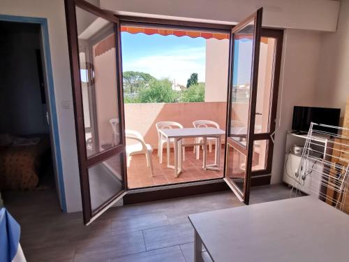 Cette chambre dispose d'une table, de chaises et d'un balcon. dans l'établissement Appartement T2 avec Tennis, Piscine et Parking à 100m de la Mer - Cap d'Agde - FR-1-607-15, au Cap d'Agde