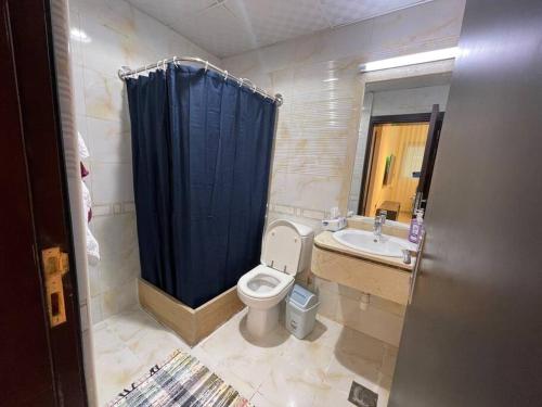 a bathroom with a toilet and a blue shower curtain at Lovely 1 Bedroom near to beach in Sharjah