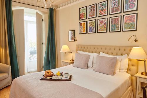 a bedroom with a bed with a tray of food on it at Alegria A Lisbon Boutique Hotel in Lisbon