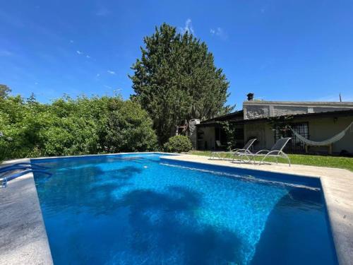 a blue swimming pool with two chairs and a house at Paz Cerca de Termas Grandes in Gualeguaychú