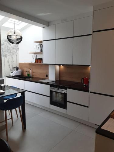 une cuisine avec des armoires blanches et une table à l'intérieur dans l'établissement Maison - 12 min Paris Saint-Lazare, à Colombes