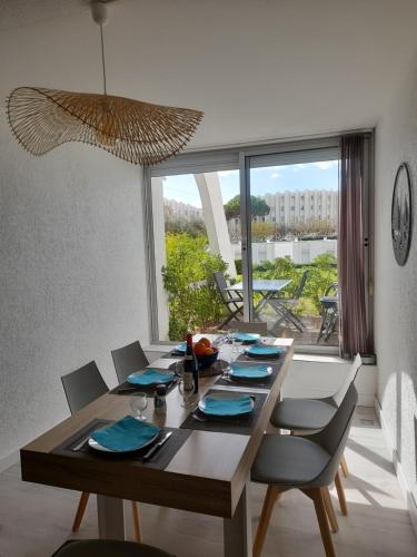 une table de salle à manger avec des chaises et une grande fenêtre dans l'établissement T2 Rez-de-jardin, terrasse et parking, proche de la plage, à La Grande Motte