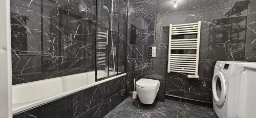 a black tiled bathroom with a toilet and a shower at Cosy'part Gold. in Bezons