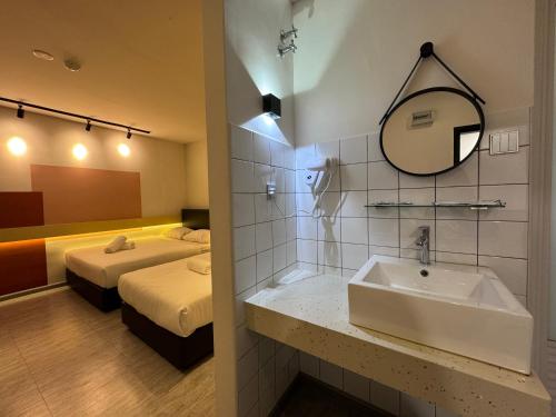 une salle de bains avec lavabo et une chambre avec 2 lits dans l'établissement Woco Hotel Kinrara, à Puchong